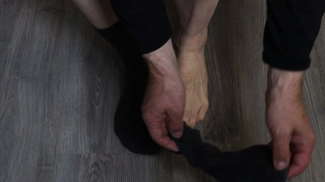A man takes off his dark socks against a gray laminate background, top view, close-up.