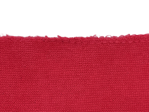 A close-up image of a textured red fabric edge against a black background, showcasing intricate weaving patterns and vibrant color.