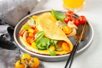 Stuffed vegetable omelette - cucumber, tomato, sweet pepper, mushrooms and spinach leaves. Healthy breakfast.