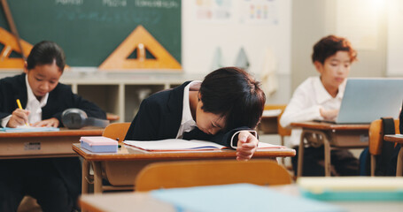 Boy child, tired and sleeping in classroom with studying, education and burnout with books at academy. Kid, fatigue and exhausted with notes, dream and rest with scholarship at school in Japan