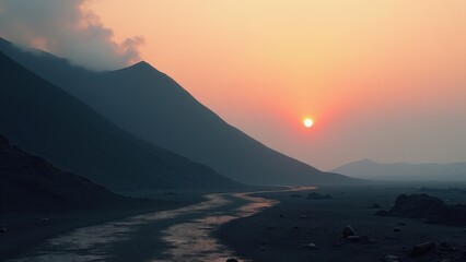 Desert valley with winding stream at sunset between silhouetted hills	