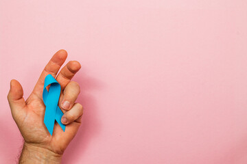 Hand holding blue ribbon symbolizes awareness for cancer prevention and support