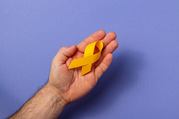Holding a yellow ribbon in support of cancer awareness and prevention efforts