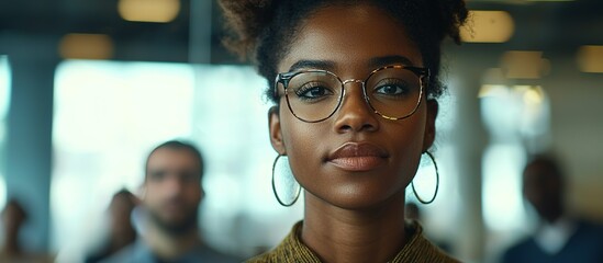 A beautiful young woman wearing stylish eyeglasses looks directly at the camera