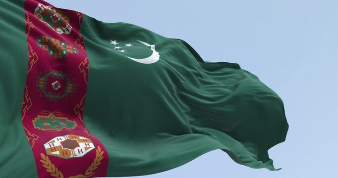 Close-up of Turkmenistan national flag waving. Green field, red vertical band, crescent moon, five stars, carpet motifs. Seamless 3d render animation. Slow motion loop. Selective focus.