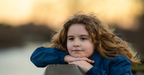 Childhood freedom. Kids portrait. Kid daydreaming in thoughts. Pretty blonde child with a dreamy look. Peaceful outdoor moment of a child. Calm and relaxed kid enjoying nature. Cute child face.