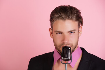 Sexy man singing into a retro microphone. Singer male model holding a microphone mic. Man sing on microphone. Jazz singer with a vintage microphone.
