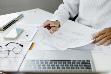 asian businessman reviewing document at office. legal expert, professional lawyer working with laptop reading and checking financial documents and business contract