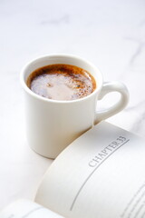 ページを開いたペーパーバック（洋書）とコーヒーの入ったコーヒーカップで、コーヒーを飲みながら読書を楽しんでいるイメージ
