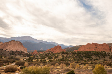 Fototapeta premium Garden of the Gods rock formations glow under afternoon sun with sparse trees and desert terrain