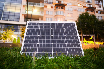 Fototapeta premium Photovoltaic solar panel in front of modern apartment building with balconies, suggesting residential or mixed-use. Concept of integration of sustainable renewable energy sources into architecture.