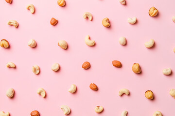Mixed nuts scattered pastel pink background, creating vibrant