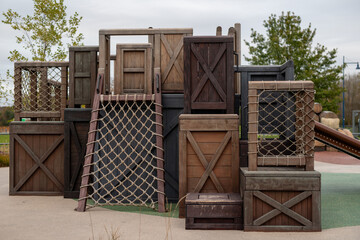 Playground structure designed as a wooden pirate ship with stairs, platforms, and netting