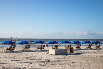Dozens of beach umbrellas and lounge chairs line the white sand under blue sky