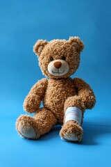 Obraz premium a seated teddy bear with on leg bandaged