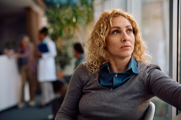 Pensive woman waiting for doctor's appointment at clinic.