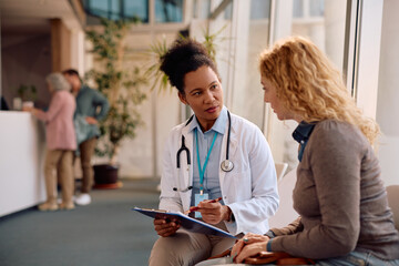 Black doctor and her female patient going through medical report at clinic. © Drazen
