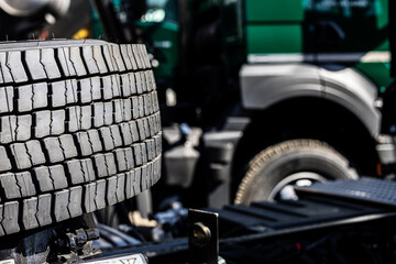 Front view of a commercial truck’s tire under the wheel arch, showing detailed tread design,...