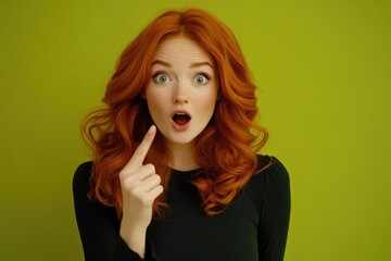 Fototapeta premium A woman with red hair is pointing at something with her finger. She has a surprised expression on her face