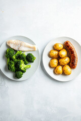Healthy fish and broccoli vs. rich sausage and potatoes, a contrast in food choices