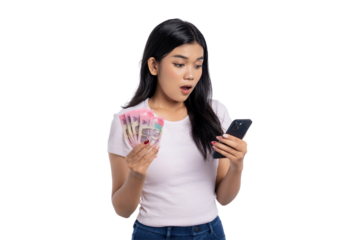 Surprised young Asian woman holding Indonesian rupiah cash and looking at smartphone, reacting to unexpected message or financial update, isolated on transparent background