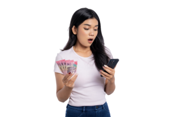 Surprised young Asian woman holding Indonesian rupiah cash and looking at smartphone, reacting to unexpected message or financial update, isolated on transparent background