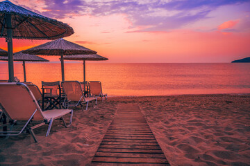 Palapa reed parasols at the beach in Vrasna, Greece in summer sunrise