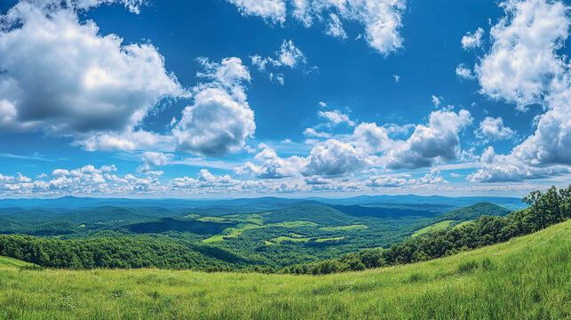 A panoramic view of rolling green hills under a bright blue sky filled with fluffy white clouds above trees