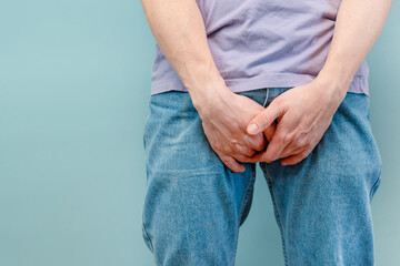 A man holds his hands between his legs for his genitals, suffering from prostatitis or from a...