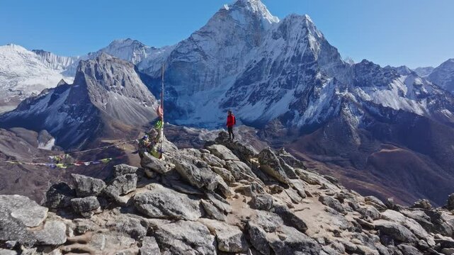 Hiker walks on Nangkartshang Peak in Nepali Himalayas, revealing sweeping panorama featuring Ama Dablam snow capped summit amid rugged mountain terrain
