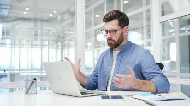 Worried businessman having problems with software or service on laptop computer while sitting at workplace in business office. Frustrated disappointed worker complains about bad internet connection