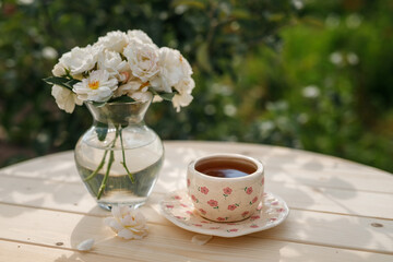 Summer still life. Beautiful roses flowers stand in a vase on a wooden table with a cup of tea.
Relaxation in the village on a sunny day. The joy of summer.