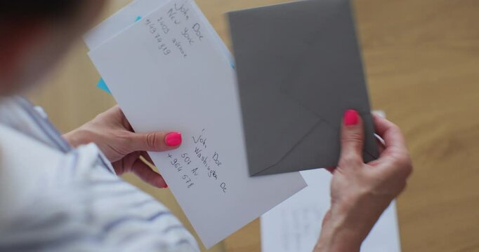 Unrecognizable woman checking mail holding papers documents. Caucasian female checking stack of letters at home.