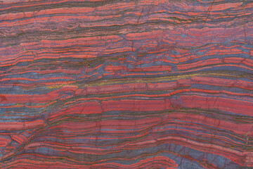 Faceted red stone with natural patterns and texture. Banded iron ore. Mineral structure, geological...