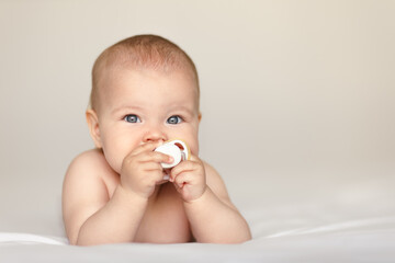 cute happy baby with pacifier lying on tummy, 5 months after birth