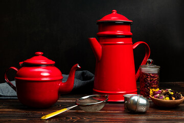 still life with vintage red metallic teapots and tea accessories on wooden table