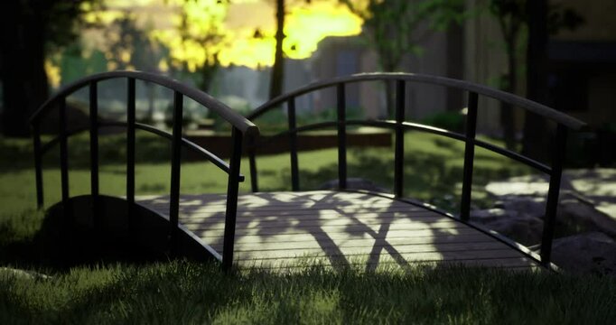 A wooden bridge arches gracefully over lush green grass in a peaceful park. Soft shadows stretch across the path as the sun sets, creating a calm and inviting atmosphere for visitors.