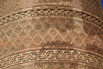 The Uzgen Minaret in the city of Uzgen was built in the 11th century during the Karakhanid period. The brick decorations on the minaret are striking.