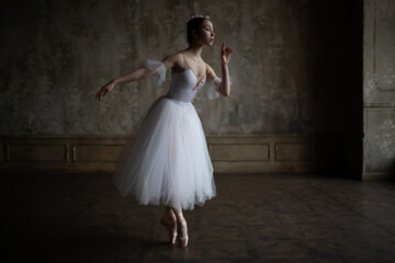 Beautiful ballerina in a white dress performs a dance.