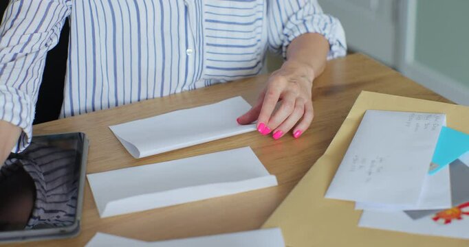 Close up female hands putting letter in envelop return form. Woman sends a return form by letter.