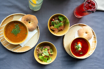 Top view of a traditional lunch with soup, salad, bread, and drinks served on a table