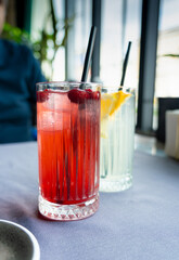 Cold lingonberry drink on restaurant table. Iced cowberry tea, refreshing cranberry cocktail
