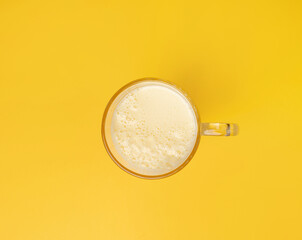 Vanilla milk shake in glass. Milkshake on yellow background, white whey protein smoothie