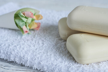 Soap and white towels on a white wooden table, close-up.