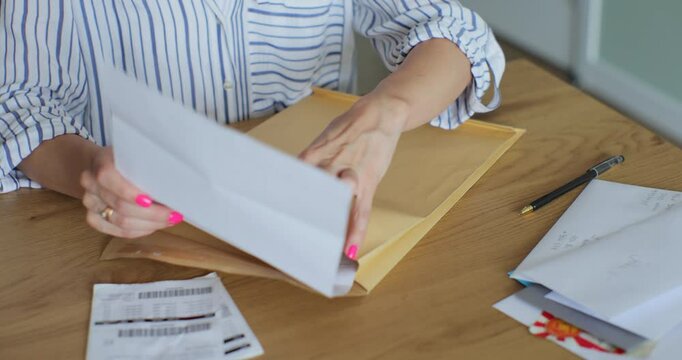 Close up female hands putting letter in envelop return form. Woman sends a return form by letter.