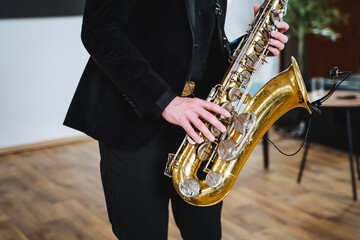 In a cozy, warmly lit room, a sophisticated man in a tailored suit passionately plays the saxophone, showcasing his talent and love for music that captivates all who hear it