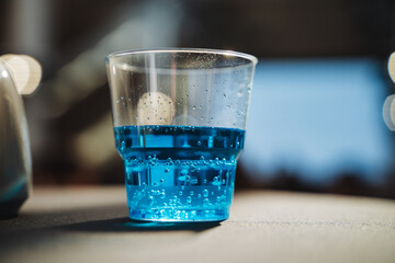 On a table, there is a glass filled to the brim with a vibrant blue liquid that looks quite...
