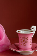 Minimalist still life with pink cup, saucer placed on dark background. Copy space
