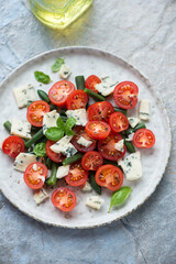 Cherry tomato, green beans and blue cheese salad, vertical shot on a blue and beige stone background, elevated view