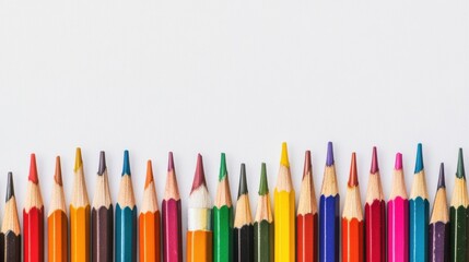 Colored pencils and paint brushes neatly arranged on a white workspace ready for creative projects during the daytime